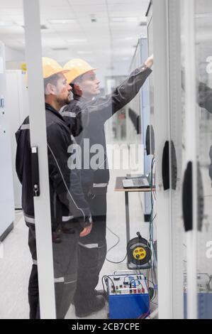 Field service crew testing electronics or inspecting electrical installation system. Bay control unit. Medium voltage switchgear Stock Photo