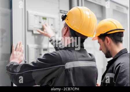 Field service crew testing electronics or inspecting electrical installation system. Bay control unit. Medium voltage switchgear Stock Photo