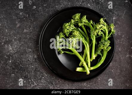 Fresh and green broccolinin in black plate on dark background Stock Photo