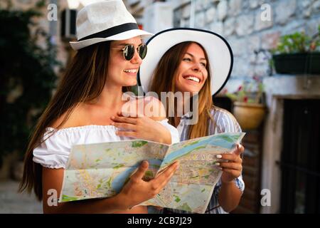 Happy young women with map in city. Travel tourist people fun concept. Stock Photo