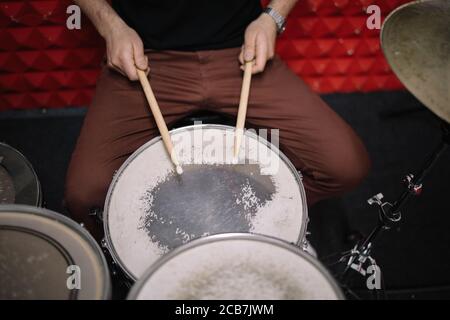 Cropped view of man playing drums in studio. Close-up view of male hands with sticks playing the drums in music studio. Stock Photo