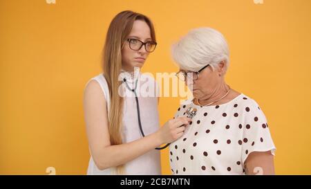 Young woman, doctor or nurse using stethoscope on senior woman. High quality photo Stock Photo