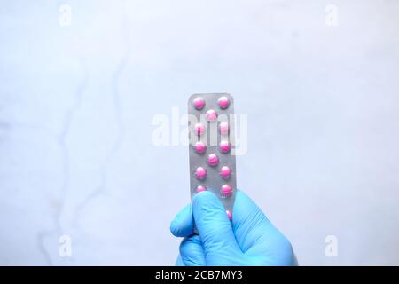 hand in protective gloves holding blister pack top view  Stock Photo