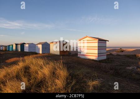 The setting sun hitting the back of some English beach huts on a beach in Kent. Stock Photo