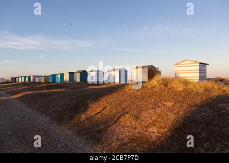 The setting sun hitting the back of some English beach huts on a beach in Kent. Stock Photo