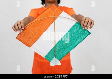 Young Indian boy holds onto a Kite with the tricolour of Indian flag, Close up of kite with Indian flag Stock Photo