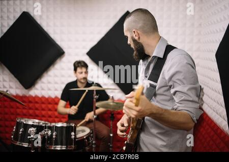 Guitarist and drummer playing in soundproof studio Stock Photo