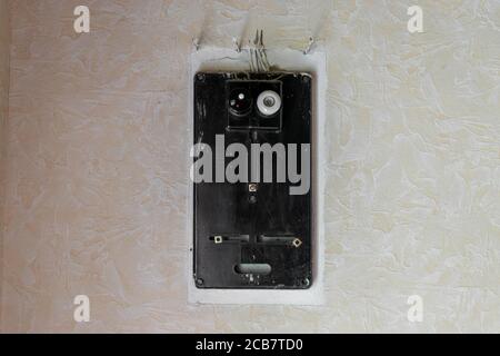 Very old black electrical fuses box hanging on white rural wall with copy space Stock Photo