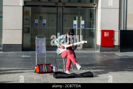 A busker playing the electric guitar to an empty High Street in Liverpool, City Centre, England Stock Photo