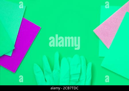 Green and pink, purple rags, green gloves on green background. Cleaning concept Stock Photo