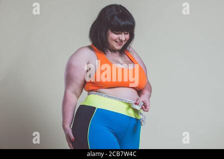 African american plus size woman in sports clothes sitting on mat