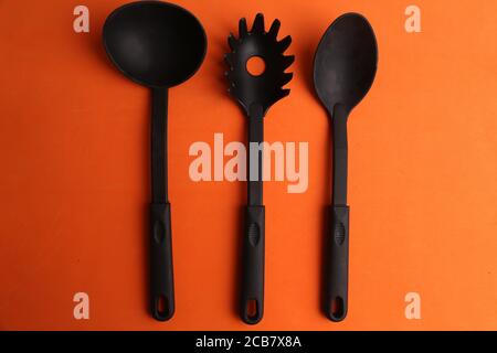 Plastic cooking utensils on an orange background Stock Photo