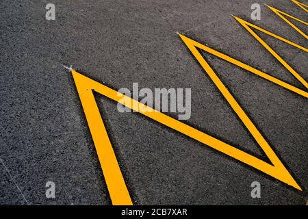 An abstract zig-zag detail of parking lot marked in yellow reflective paint. Stock Photo