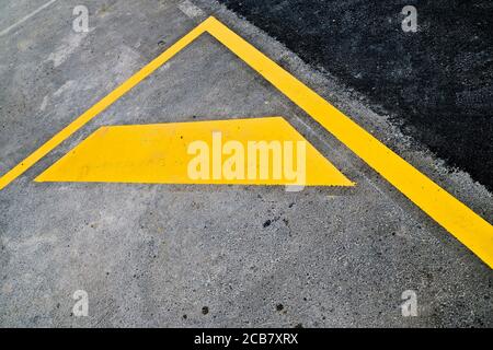 Abstract fragment of yellow road signage - parking lot markings on black road surface. Stock Photo