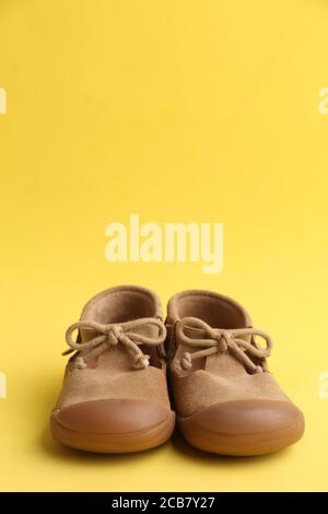 Vertical shot of brown shoes isolated on yellow background Stock Photo