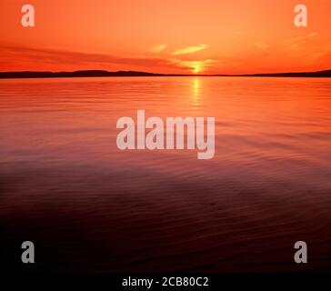 Sun setting over calm smooth Lake Superior in the upper Peninsula of Michigan in the United States Stock Photo
