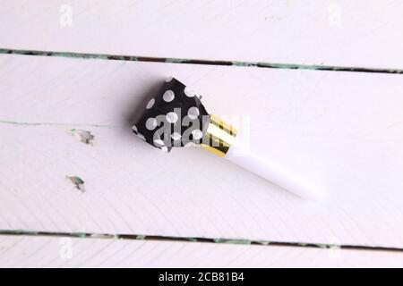High angle top view closeup shot of a polka-dotted party whistle on a wooden table Stock Photo