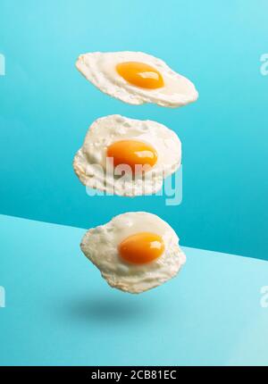 Three flying eggs on the modern blue background Stock Photo