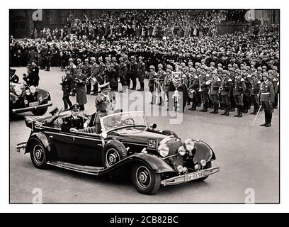 1940's Adolf Hitler in his open top Mercedes limousine salutes the German crowds in a victory parade in Berlin after his successful invasion of France His personal Liebstandarte SS 1st Panzer Division in foreground WW2 World War II Stock Photo