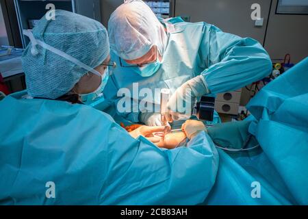 two doctors operate on a wrist fracture in an operating theatre Stock Photo