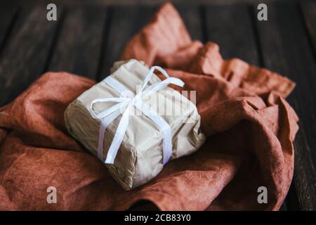 Gift wrapped in brown paper on a piece of fabric