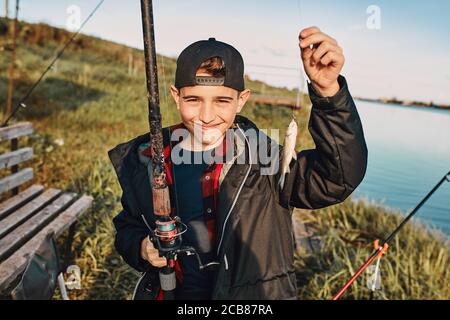 Teen Caucasian Boy Caught First Fish. He Hold Fishing Rod And Fish. Stock  Photo, Picture and Royalty Free Image. Image 132751486.