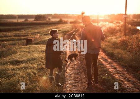 Father found good place for fishing. Son follow. Sunset. Stock Photo