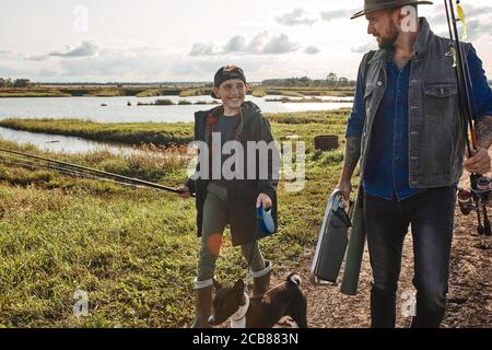 Father and teen son fishing near lake. Father stand, wait for fish