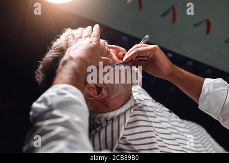 professional stylist working eith straight razor, close up side view photo Stock Photo