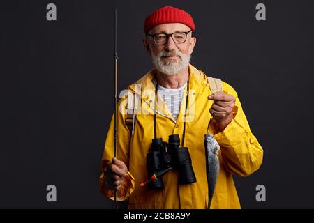 Bearded adult man posing with fish near river in summertime Stock
