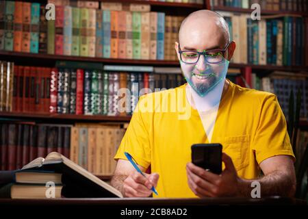 Biometric verification. Young bald man with the phone. The concept of a new technology of face recognition on polygonal grid is constructed by the poi Stock Photo