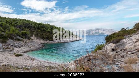 Hidden cove beach on the island of Brac, Croatia. Rocky shore with forest trees surrounding the small paradise. Area in front of the hidden bunker bel Stock Photo