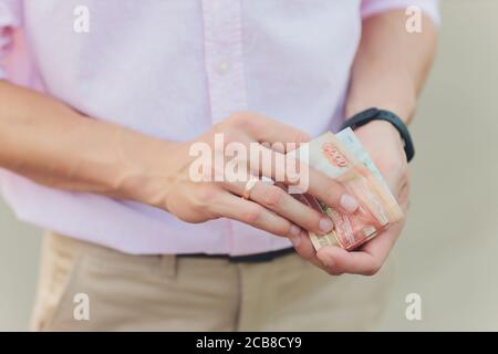 A close up photo of a Caucasian male hand holding a 100 Russian ruble note. Stock Photo