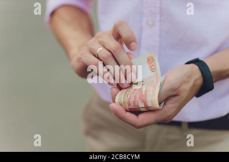 A close up photo of a Caucasian male hand holding a 100 Russian ruble note. Stock Photo