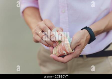 A close up photo of a Caucasian male hand holding a 100 Russian ruble note. Stock Photo