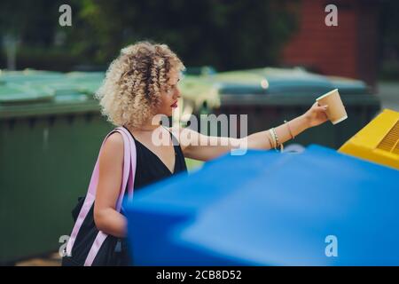 Woman using waste separation container throwing away coffee cup made of Styrofoam. Stock Photo