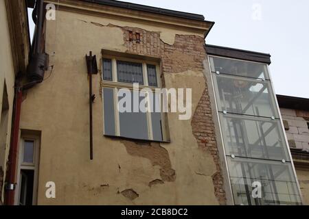 On a street called Klimentska in Prague, you can see some buildings in a state of disrepair, with broken parts of exterior walls, exposing bricks. Stock Photo