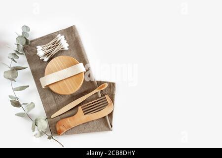 Zero waste concept. Set of eco friendly bamboo toothbrush, cotton buds, natural hairbrush and eucalyptus branch on linen napkin.Sustainable lifestyle. Stock Photo