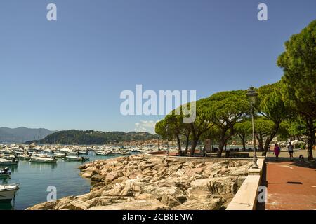 View of the seaside promenade with people walking and the harbor of the sea town on the shore of the Gulf of the Poets, Lerici, La Spezia, Italy Stock Photo