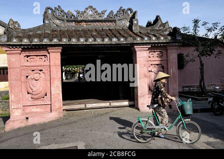 Woman with her bicycle in front of Japanese covered bridge in Hoi An, Vietnam Stock Photo