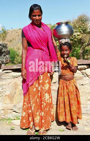 Charming Indian girls from poor family  with traditional water pot on the head. India, Rajasthan. feb 2013 Stock Photo