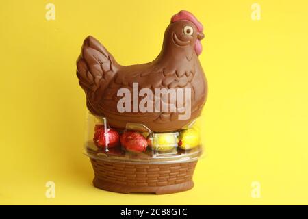Closeup of a chocolate chicken with eggs for Easter isolated on a yellow background Stock Photo