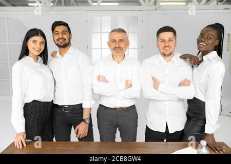 Group picture of happy diverse multiethnic young businesspeople in white shirts posing together at workplace in office Stock Photo