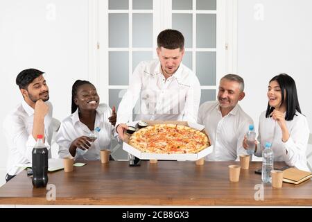 Lunch break. Young employees ordered pizza to the office and have lunch together in their office Stock Photo