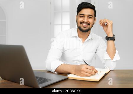 Asian student studying, learning language, online education concept. Portrait of handsome Indian businessman using laptop computer, working in office