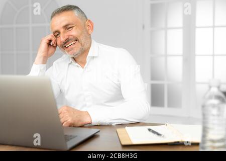 Successful businessman working on laptop in modern luxury office desk. Young entrepreneur satisfied with work result analyzing financial indicators on Stock Photo