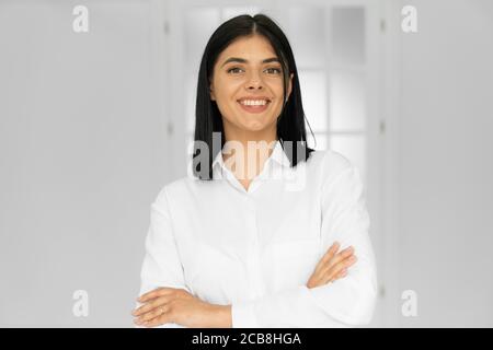 Portrait of charming accountant, nice lawyer in white shirt standing with crossed arms in work station place Stock Photo
