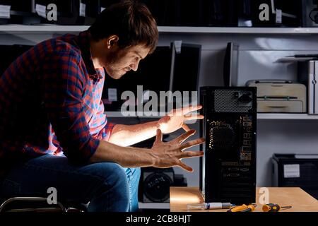 hardware problem concept.funny man using magic skills while repairing a computer, close up side view photo, emotional man enthusiastic about repairing Stock Photo