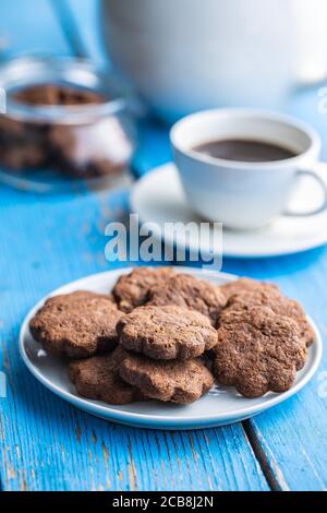 Sweet cookies. Crunchy chocolate biscuits shape flower on plate on blue wooden table. Stock Photo