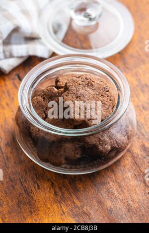 Sweet cookies. Crunchy chocolate biscuits shape flower in jar on wooden table. Stock Photo